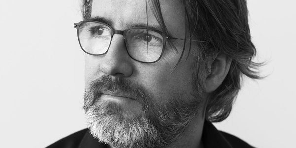 A bearded man wearing glasses, Olafur Eliasson, gazes towards the side.