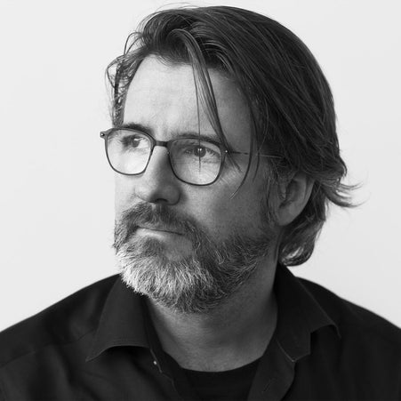 A bearded man wearing glasses, Olafur Eliasson, gazes towards the side.