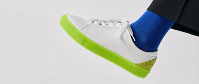 Low top white sneakers with a bright sole by Diverge, promoting social impact and custom shoes.