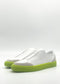 The SO0049 White & Fluorescent Yellow slip-on sneakers feature neon green soles and are handcrafted in Portugal from premium Italian leathers, set against a plain white background.