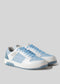 Pair of light blue and white retro-future sneakers with blue laces and a grey heel, handcrafted in Portugal using premium Italian leathers, displayed on a plain grey background.