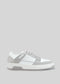 M0009 by Nuno, a white and grey casual sneaker made from premium Italian leathers, with light grey laces, featuring a white sole and minimalist design, viewed from the side against a grey background. Handcrafted in Portugal for a touch of retro-future elegance.