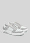 A pair of white and light gray athletic sneakers, handcrafted in Portugal using premium Italian leathers, with white laces on a light gray background—M0009 by Nuno.