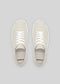 Top view of a pair of V1 Antique White handcrafted sneakers with white laces on a gray background.