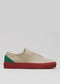 The V43 Beige W/ Red sneaker features a beige exterior with a red sole and green accent on the heel, showcased against a light gray background. It is expertly handcrafted in Portugal using premium Italian leathers.