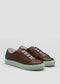 The V42 Brown W/ Pastel Green sneakers, crafted with premium Italian leathers in a brown and teal color scheme and a light green sole, are showcased against a plain gray background.