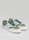 The V28 Pine & Grey low top sneakers, handcrafted in Portugal with premium Italian leathers, feature a green and white design with teal laces and rest elegantly on a plain background.