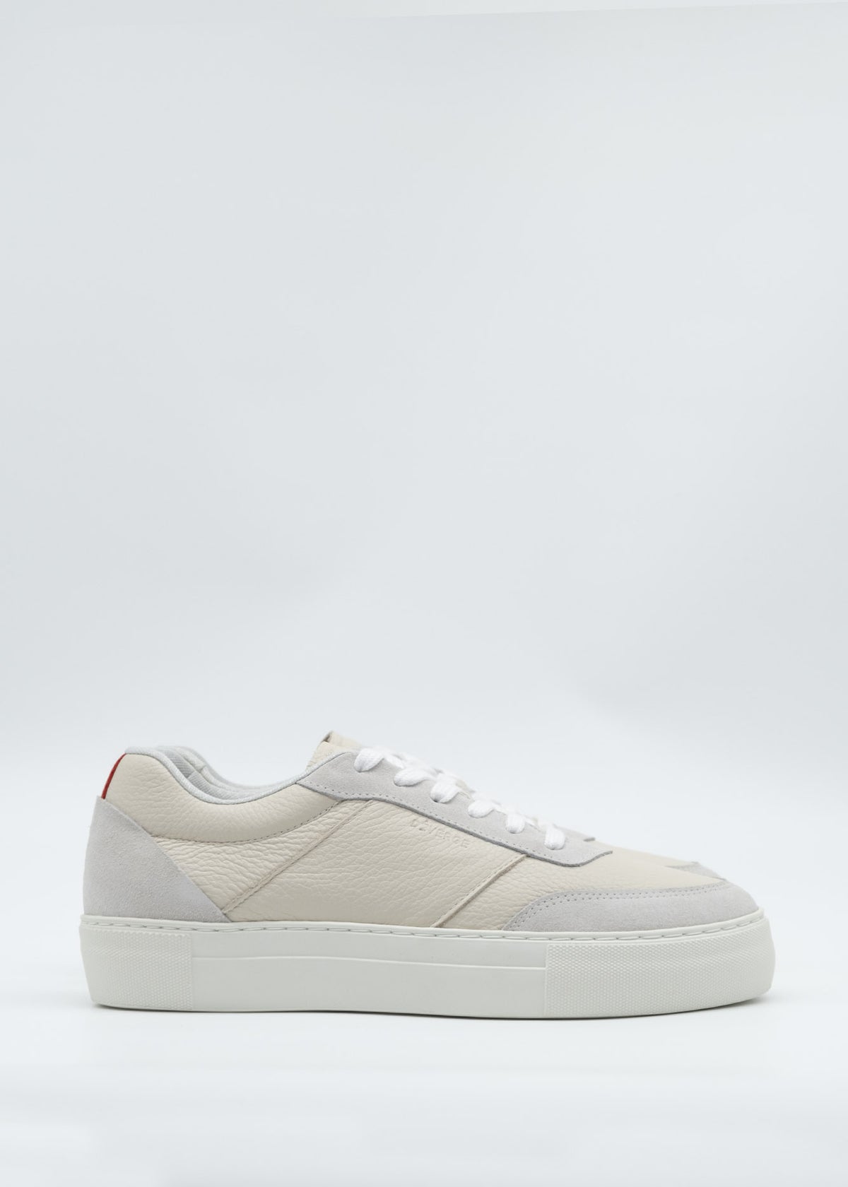 N0025 Beige Floater is a white low-top sneaker crafted from premium Italian leathers, featuring a textured finish, white laces, and a thick rubber sole. It is handcrafted in Portugal.