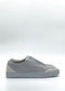 Side view of the SO0038 Grey & White slip-on sneaker, handcrafted in Portugal with premium Italian leathers, featuring a minimalist design and a white rubber sole, set against a plain white background.