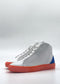 The MH0138 White & Orange high-top sneakers are handcrafted in Portugal from premium Italian leathers and feature bright orange soles and blue accents on the heels, set against a plain background.