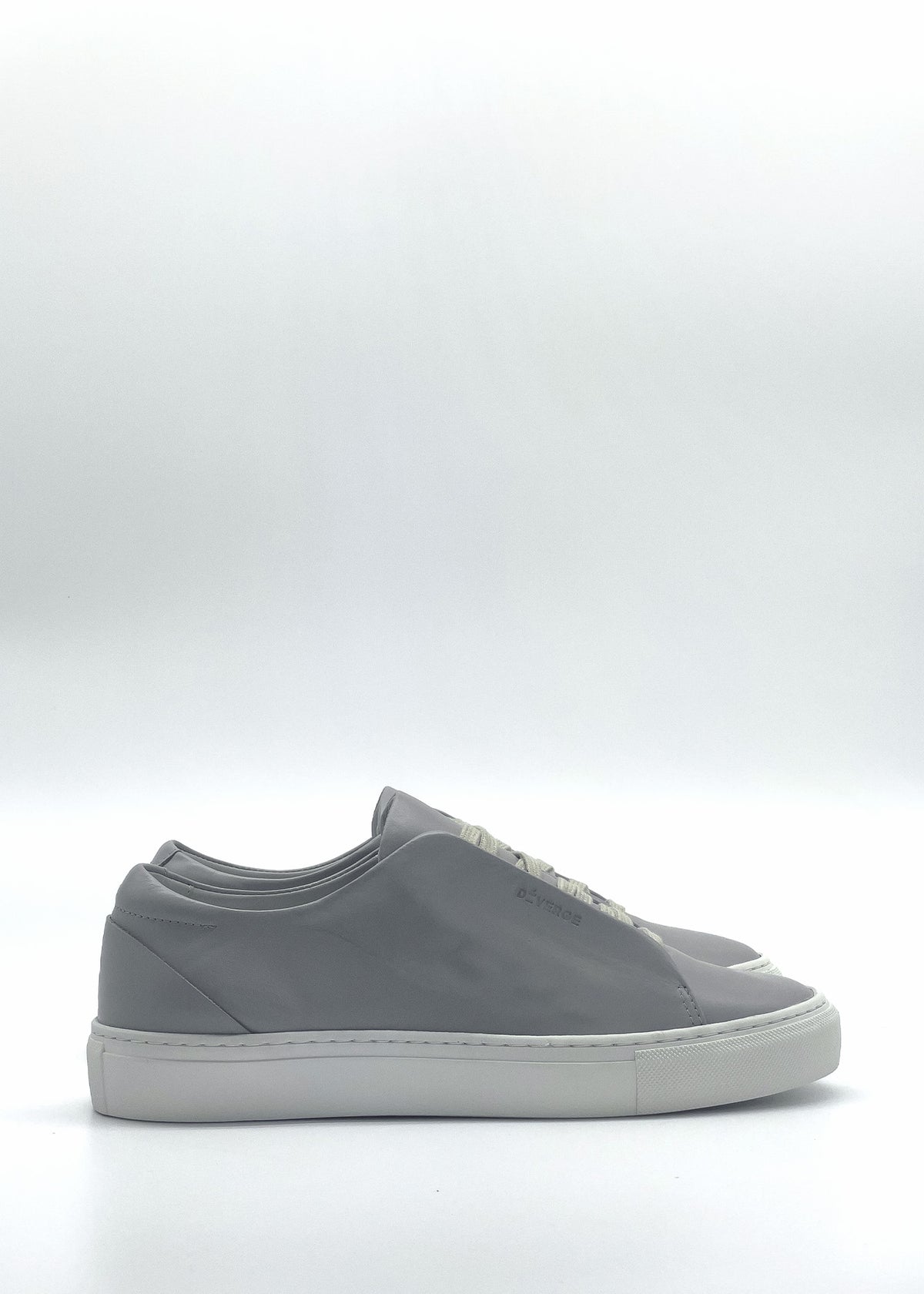 Side view of the ML0109 Grey low-top sneakers, featuring gray uppers with white soles and laces, showcased on a plain white background. These shoes are handcrafted in Portugal with premium Italian leathers and ethically made to order.