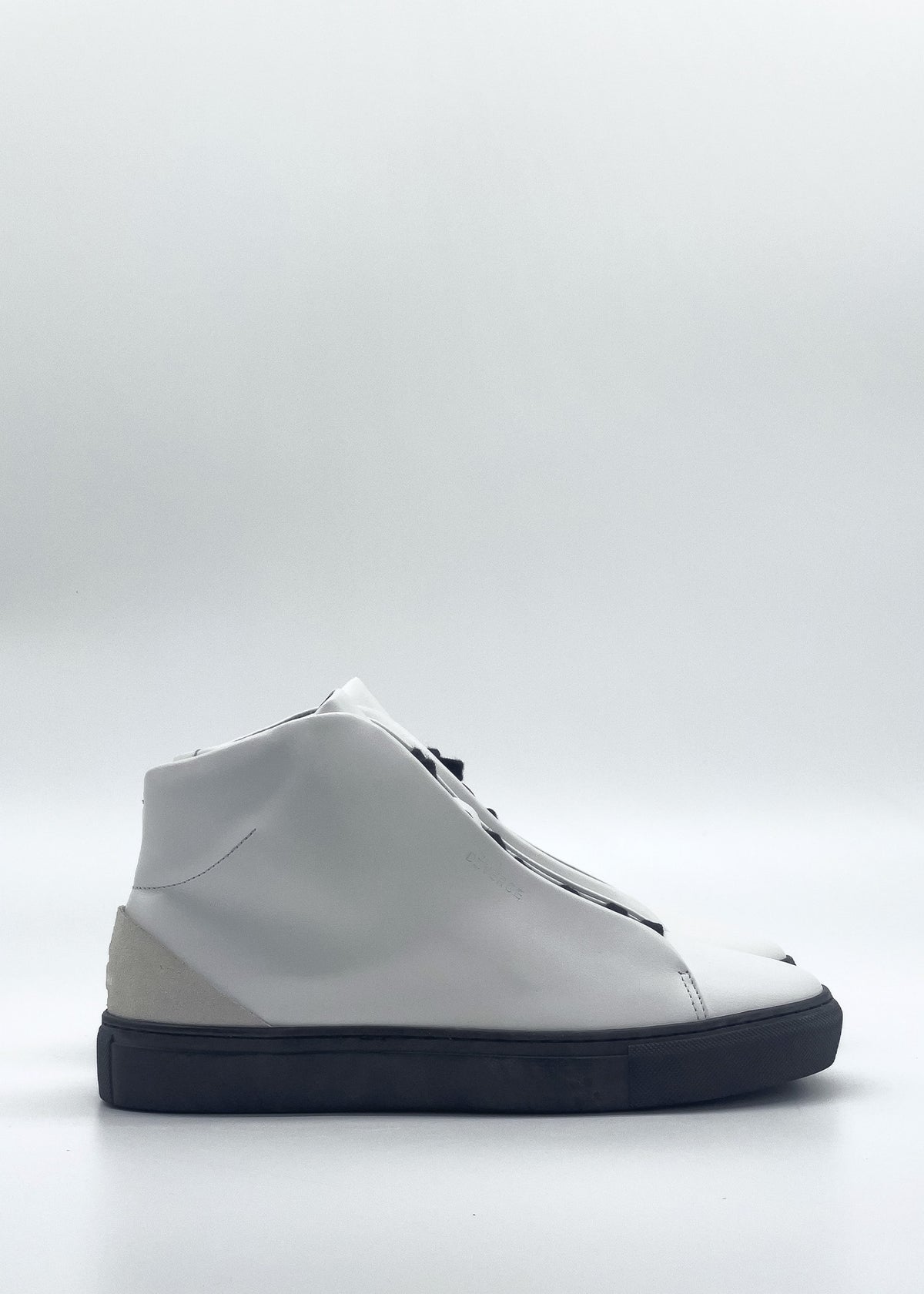 Introducing the MH0142 White & Black: a high-top sneaker featuring a sleek white design with a contrasting black sole, meticulously crafted from premium Italian leathers. Showcased in a side view against a simple backdrop, each pair is ethically handmade to order in Portugal.