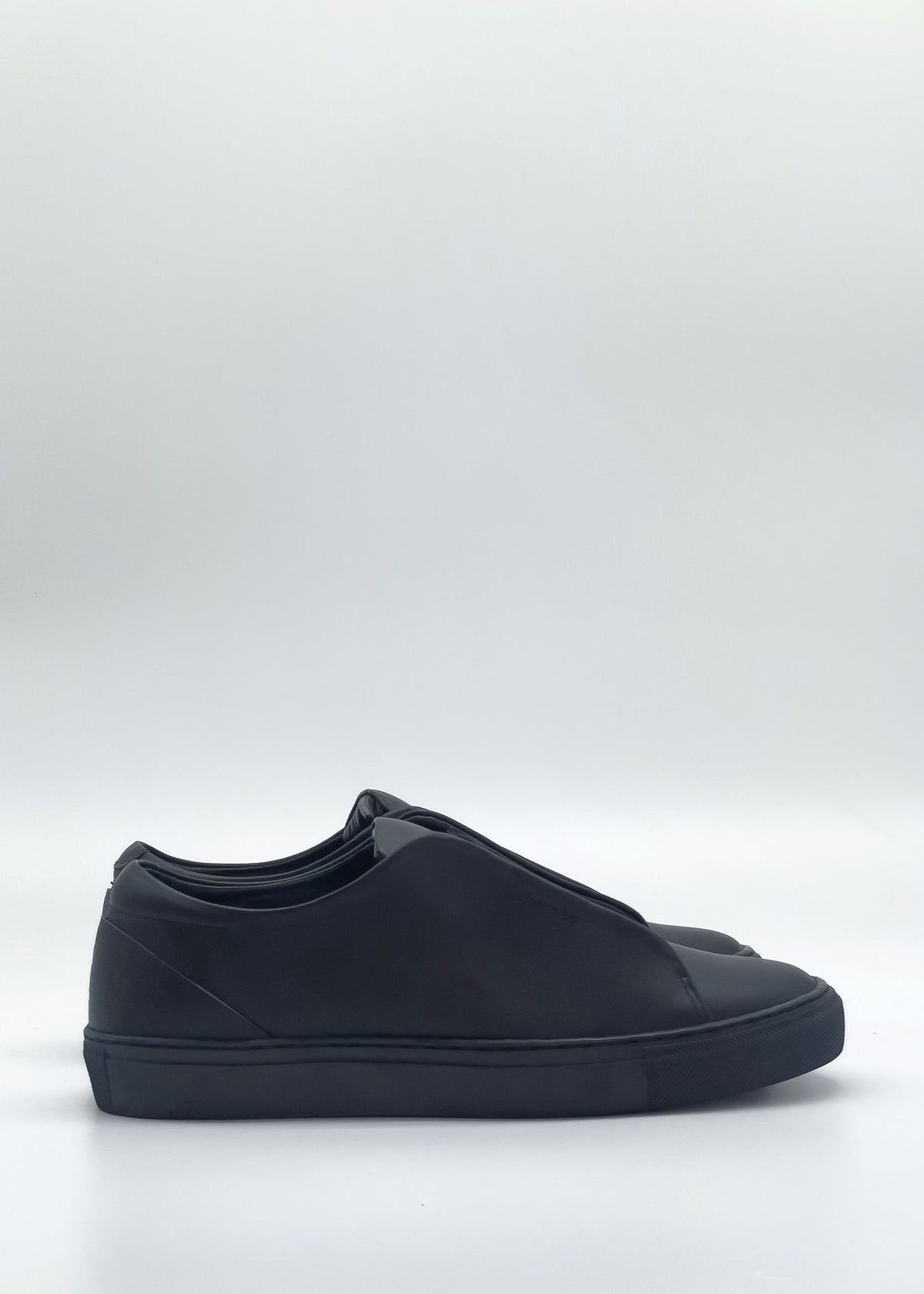 The ML0107 Black slip-on sneakers are handcrafted in Portugal, featuring a smooth and minimalist design made from premium Italian leather, showcased on a plain white background.