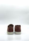 A pair of ML0115 Caramel handcrafted sneakers with brown uppers and white soles, constructed from premium Italian leathers, viewed from behind on a plain white background.