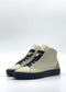 Introducing the MH0146 Beige & Black: A pair of handcrafted high-top sneakers made from premium Italian leathers in white, featuring contrasting black soles and laces. The tan suede accents on the heel provide a touch of elegance. These sneakers are ethically made to order, presented against a plain white background.