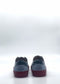 A pair of handcrafted sneakers, known as the SO0039 Blue & Red, featuring a gray upper and red soles, viewed from behind against a plain white background.