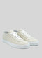 The V1 Antique White sneakers are beige handcrafted shoes that boast premium canvas material, equipped with white laces and white rubber soles, set against a light gray background.