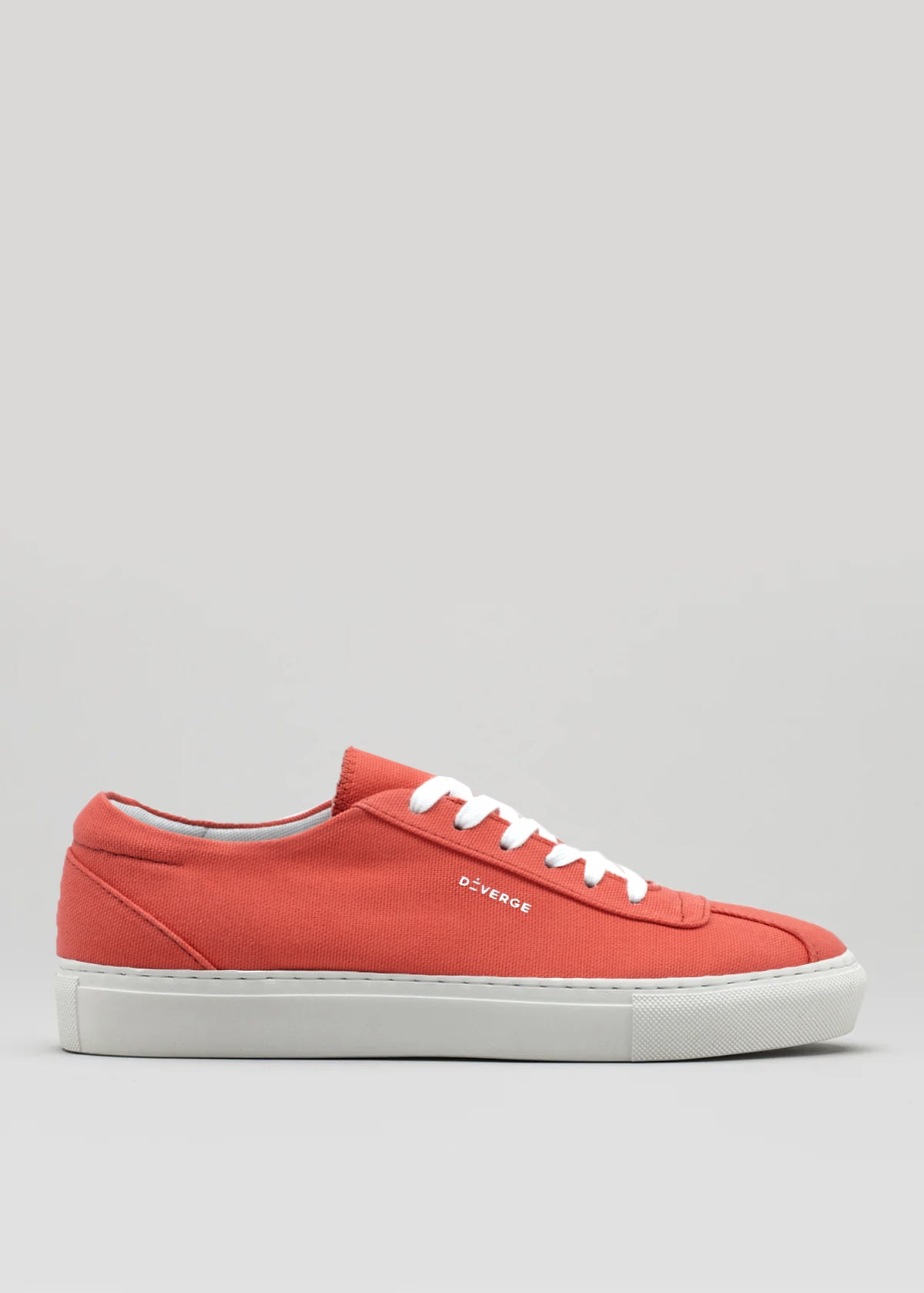 The V2 Geranium is a handcrafted red low-top sneaker made in Portugal, featuring white laces and a sleek white sole, displayed against a plain background.