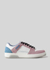 The M0019 by Rita sneaker features a white base with pink suede overlays and blue accents using premium Italian leathers. It includes black laces and a textured white sole, all set stylishly against a gray backdrop for a retro-future design flair.