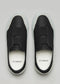 V19 Black Leather W/ Bone slip-on sneakers featuring elastic bands, made from premium leather, displayed from an overhead angle on a gray background.