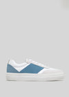 The N0017 by Raquel are handcrafted sneakers in premium Italian leathers, boasting a white design with a blue stripe and beige accents against a gray background.