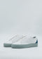 A pair of ML0096 White & Green sneakers, featuring sleek white leather with light gray soles and a dark teal section on the heel, crafted from premium Italian materials, displayed against a plain light background.