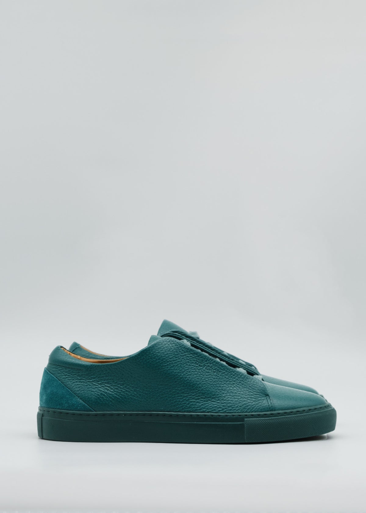 Discover the ML0102 Emerald Green Floater sneakers, featuring a minimal low design in dark green, expertly crafted from premium Italian leathers set against a light gray backdrop.