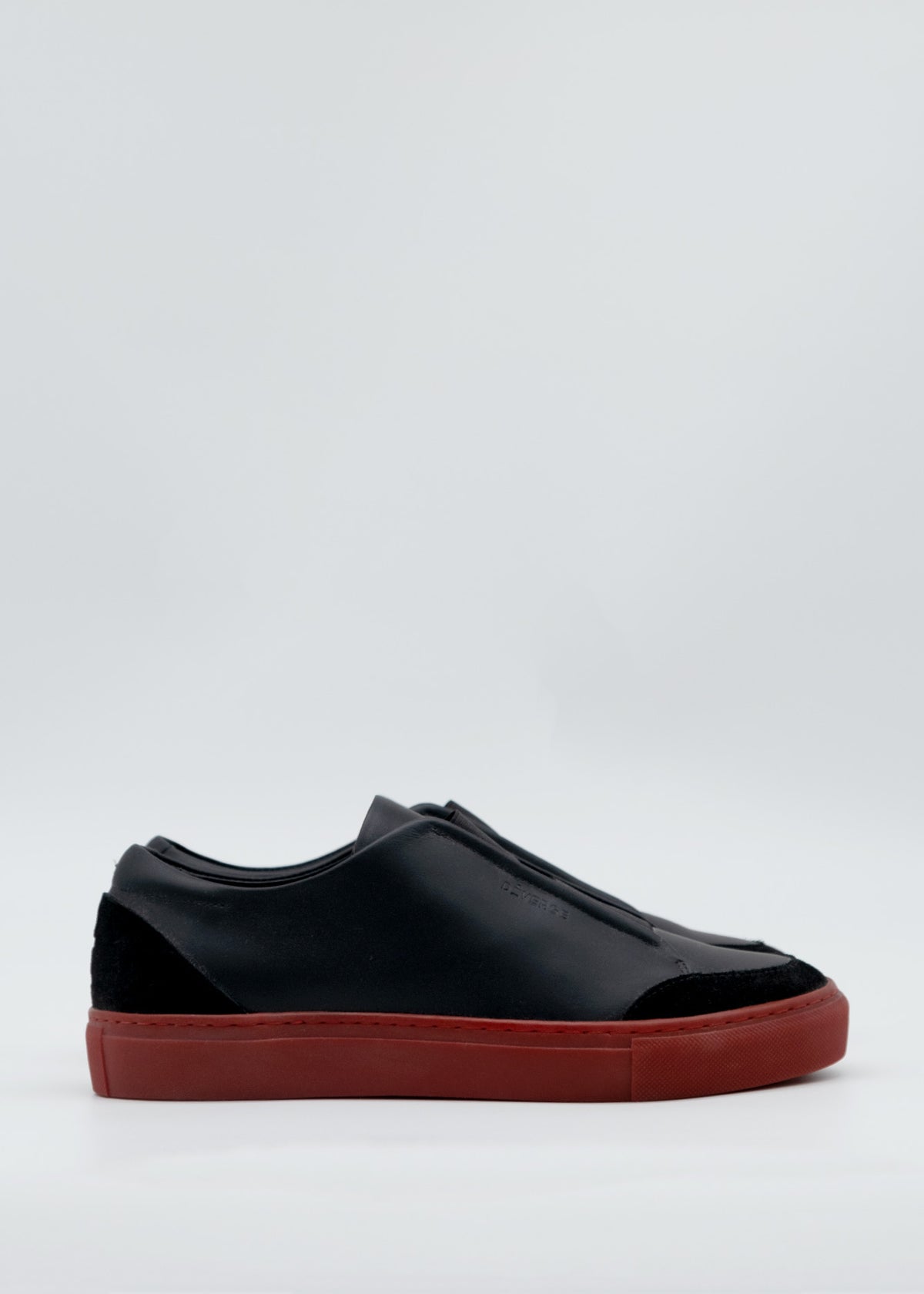 Product Description: The SO0036 Black & Red sneaker features a side view showcasing its black design made from premium Italian leathers, paired with a striking red sole, set against a plain white background. Expertly handcrafted in Portugal.