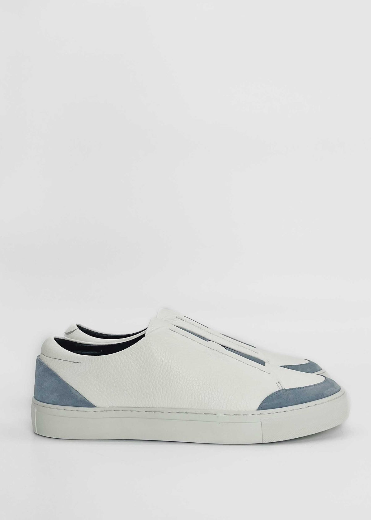 A pair of SO0028 White W/ Blue with light blue accents and a low-top design, handcrafted in Portugal using premium Italian leathers, viewed from the side against a plain background.