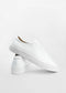 A pair of ML0038 White Leather low-top sneakers are displayed against a plain white background. One shoe is standing upright while the other is propped against it at an angle, showcasing their handcrafted premium Italian leathers.