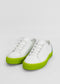 A pair of ML0062 White W/ Blue sneakers handcrafted in Portugal, featuring bright green soles and white laces, set against a plain white background.