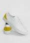 A pair of ML0085 White W/ Yellow with a yellow patch on the heel. Handcrafted in Portugal from premium Italian leathers, one sneaker is placed upright resting its sole on the other sneaker lying flat.