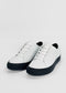 A pair of ML0070 Vegan White W/ Black with black soles, handcrafted in Portugal from premium Italian leathers, viewed from an angle against a plain white background.