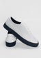 A pair of white low-top sneakers with black soles, handcrafted in Portugal from premium Italian leathers. The name "ML0070 Vegan White W/ Black" is printed on the heel section of one shoe.