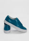 A pair of ML0083 Blue Leather slip-on sneakers with white soles, handcrafted in Portugal and made from premium Italian leathers, one shoe resting on top of the other, displayed on a plain white background.