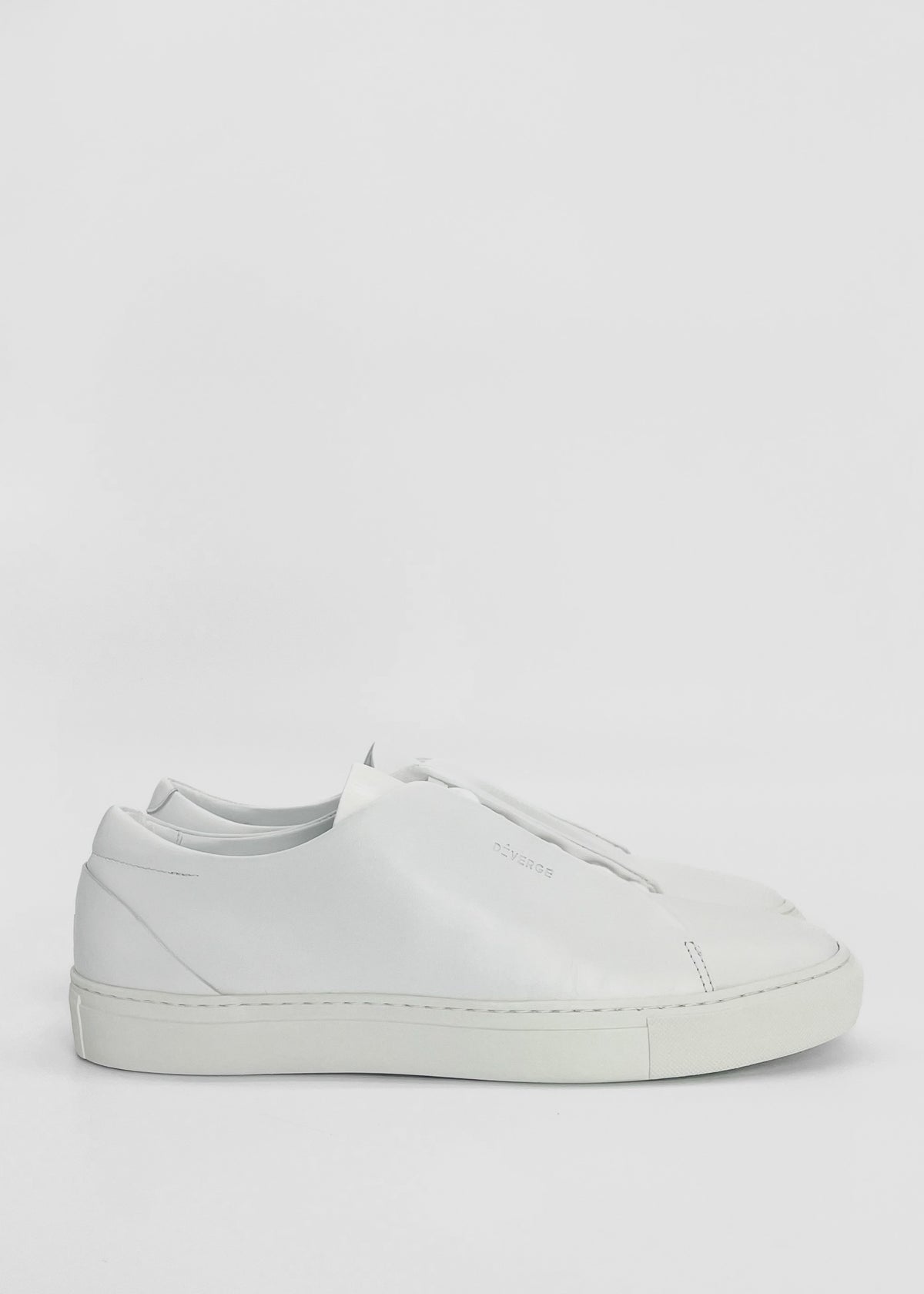 A white, minimalist sneaker with a flat sole displayed against a plain background. Handcrafted in Portugal from premium Italian leathers, the ML0065 White Leather has a smooth finish and subtle branding near the laces.