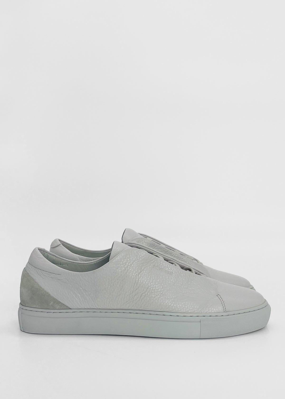 A pair of ML0072 Grey Floater W/ Plaster, handcrafted in Portugal using premium Italian leathers, is shown against a plain white background. The shoes feature a simple, clean design with white rubber soles and laces, with no visible branding. Ethically made to order.