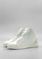 Product Description: The MH0118 White Leather W/ Bone high-top sneakers, meticulously handcrafted in Portugal, feature elegant lace-up fronts and stylish light-colored midsoles, showcased on a minimalist gray background.