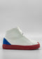 The MH0119 White W/ Electric Blue sneaker features a white high-top design, a red sole, blue accents on the heel, and white laces. These sneakers are set against a plain background and are handcrafted in Portugal from premium Italian leathers.