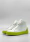 The MH0120 White Leather W/ Lime sneakers are meticulously crafted from premium Italian leathers and showcase striking white high-tops with vibrant lime green soles and suede heel accents, presented against a plain backdrop. These exceptional shoes are handcrafted in Portugal.