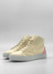 The MH0123 Beige Leather W/ Pink high-top sneakers feature beige uppers crafted from premium Italian leathers, complemented by white soles and a pink accent on the heels. Set against a plain background, these shoes are handcrafted in Portugal and ethically made to order, effortlessly combining style and sustainability.