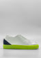 Side view of the ML0089 White Leather W/ Blue sneaker, featuring a bright lime green sole and heel. The back of the shoe is navy blue, and there are no visible laces. Handcrafted in Portugal using premium Italian leathers, this sneaker embodies both style and quality.