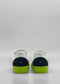 Rear view of white sneakers with blue accents and bright green soles against a plain gray background. The brand logo "MiM" is visible on the heel. These shoes, ethically made and handcrafted in Portugal, exude both style and responsibility. They are the ML0089 White Leather W/ Blue model.