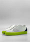 ML0089 White Leather W/ Blue, a pair of white low-top sneakers handcrafted in Portugal from premium Italian leathers, featuring neon green soles and a black heel accent, set against a plain grey background.