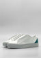 The ML0090 White Floater W/ Emerald Green sneakers, handcrafted in Portugal from premium Italian leathers, feature an emerald green accent on the heel and are showcased against a plain, light grey background.