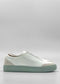 Side view of the SO0031 White Leather W/ Green slip-on sneaker featuring a light green sole and accents. Ethically made to order, this shoe boasts a minimalist design with subtle stitching and a smooth finish. Handcrafted in Portugal, these sneakers promise both style and sustainability.