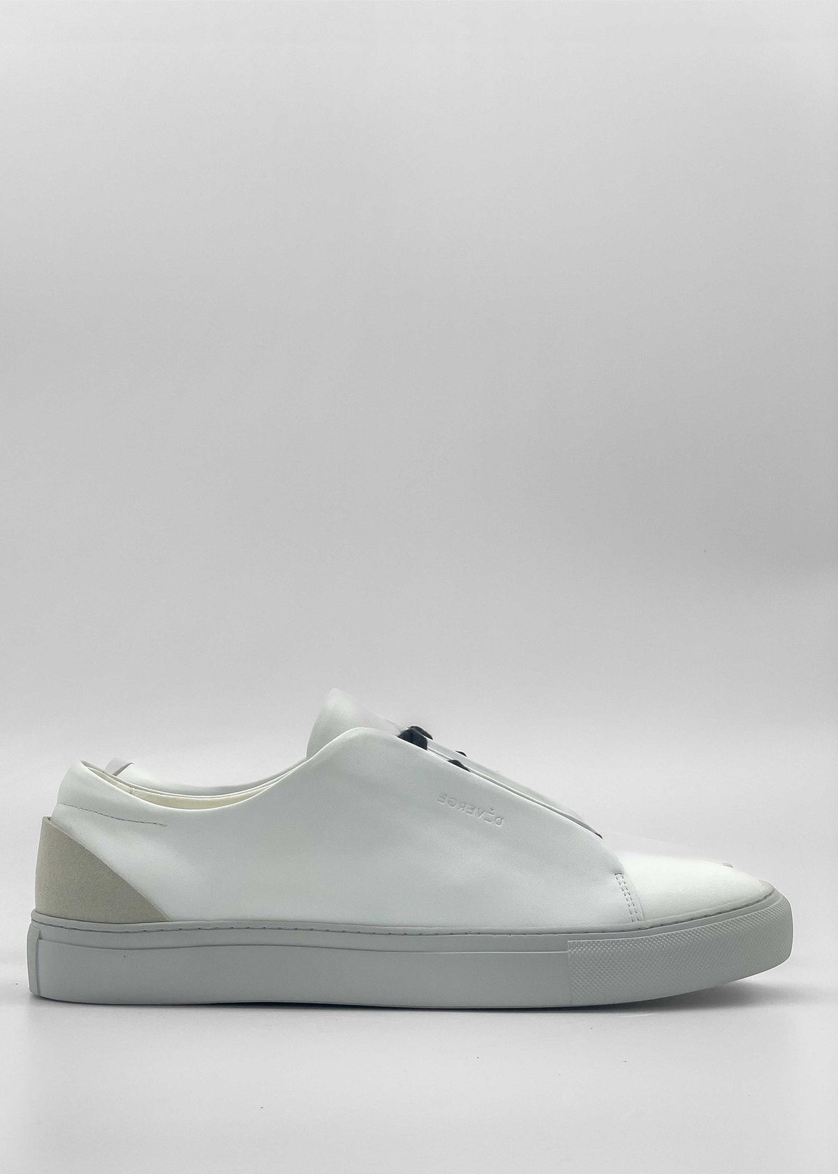 A side view of the ML0091 White Vegan W/ Grey sneaker, featuring a white sole and light beige detail on the heel, handcrafted in Portugal from premium Italian vegan leathers. The minimalist design showcases a clean look with no visible laces. The background is plain white.