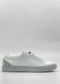 A side view of the ML0091 White Vegan W/ Grey sneaker, featuring a white sole and light beige detail on the heel, handcrafted in Portugal from premium Italian vegan leathers. The minimalist design showcases a clean look with no visible laces. The background is plain white.