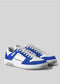 A pair of Build white and blue athletic sneakers with white laces, handcrafted in Portugal, set against a plain light gray background.