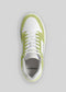 Top view of a single white V10 Brat sneaker with light green suede accents, white laces, and perforations on the toe area. The insole proudly displays "DEVERGE" printed in black. These meticulously handcrafted sneakers feature premium Italian leathers, offering a perfect blend of style and comfort.